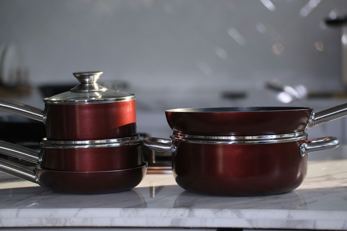 Casseroles rouges empilées avec couvercles en verre sur plan de travail cuisine moderne - astuces rangement couvercles