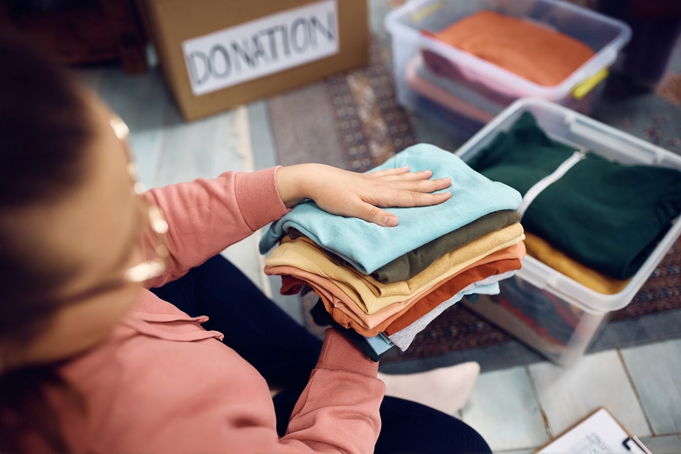 Femme triant méthodiquement les vêtements de son dressing, avec piles organisées et sacs de don