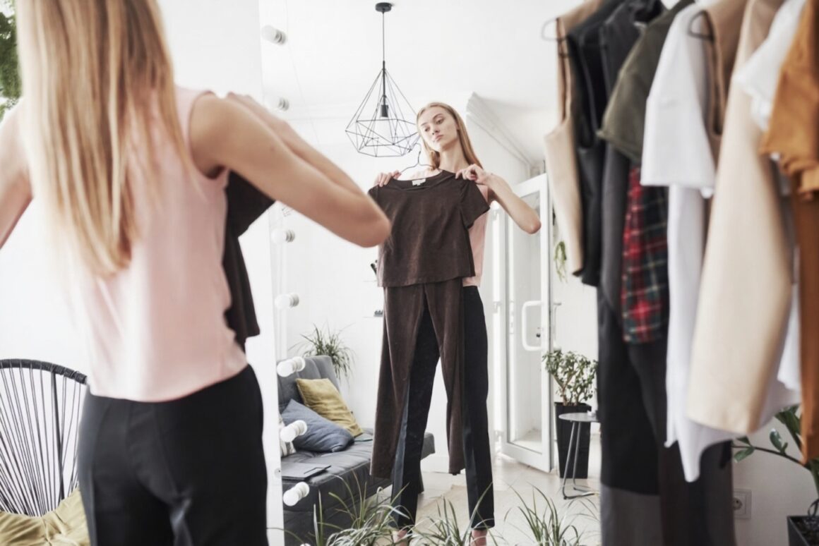 Femme souriante choisissant facilement une tenue dans son dressing bien organisé