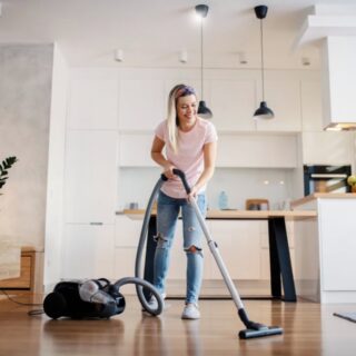 Femme détendue assise dans son salon parfaitement rangé, sourire satisfait, lumière naturelle