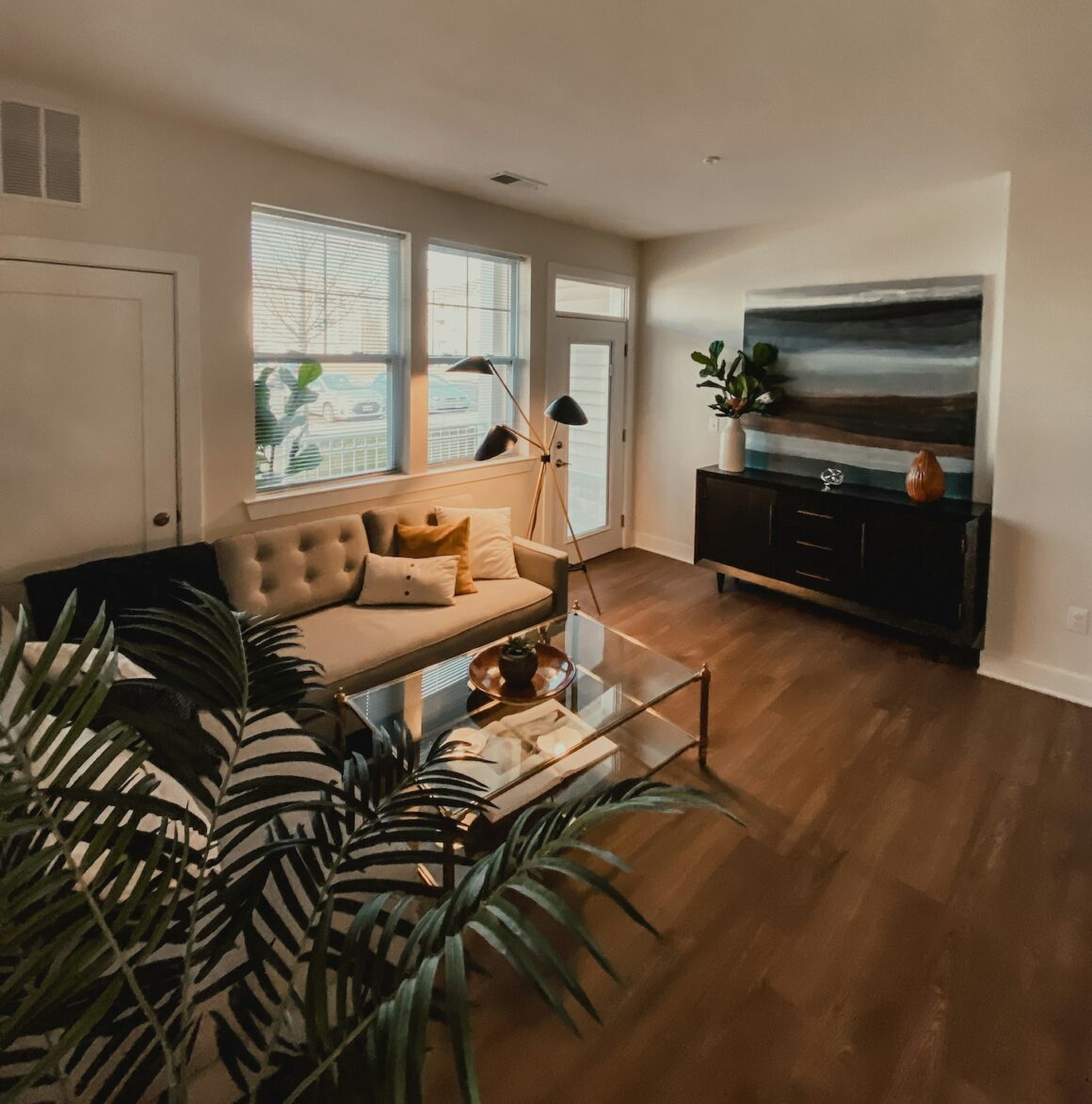 Salon moderne et rangé avec canapé beige, coussins bien disposés et surfaces dégagées