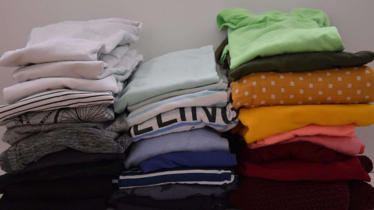 Mains pliant un t-shirt selon la technique de pliage vertical