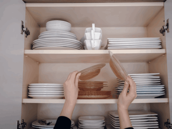 Placard de cuisine organisé avec tupperware et boîtes alimentaires empilés et rangés par taille sur des étagères en bois clair