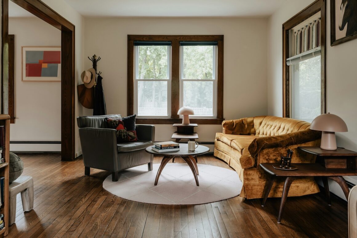 Table basse épurée avec seulement une bougie et un livre, salon lumineux en arrière-plan
